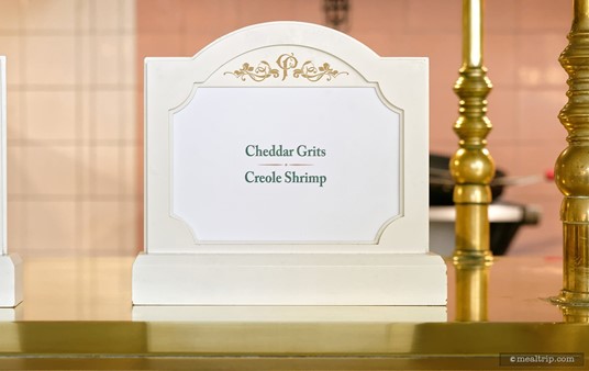 These little "buffet name plate signs" are located on the counter, directly over the item, which is under the "sneeze guard". It'll all make sense when you see it in person.