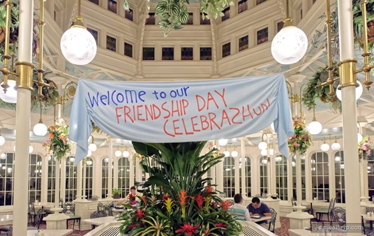 A "Welcome to our Friendship Day Celebration" banner hangs from two pillars on near the room's centerpiece atrium.