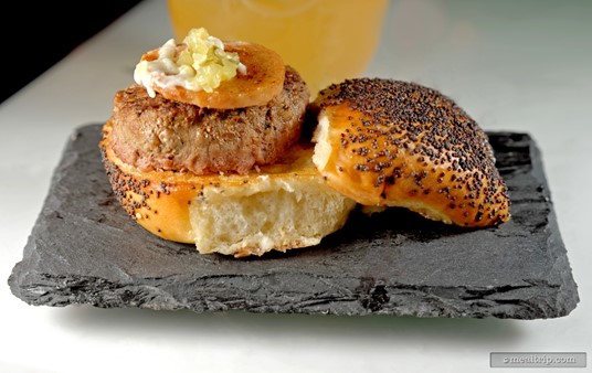 That's just a great looking Poppy Seed Bun! In addition to that, there's a Grass Fed Beef Patty topped with an All Beef Hot Dog. Along for the ride is a small dapple of Relish and a Havarti Cheese Sauce.