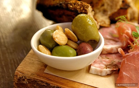 Mixed olives and almonds are in a small bowl on the Artist Point charcuterie board.