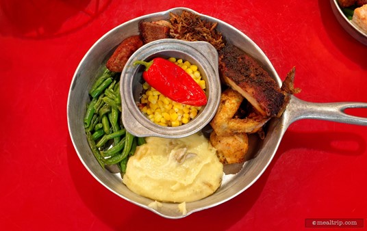 The Traditional Signature Skillet at Whispering Canyon Cafe includes oak-smoked mustard-barbecued beef brisket, maple-chipotle pork ribs, slow-smoked pulled pork, citrus-herb chicken, western-style sausage, smashed potatoes, buttered corn, and sautéed green beans.