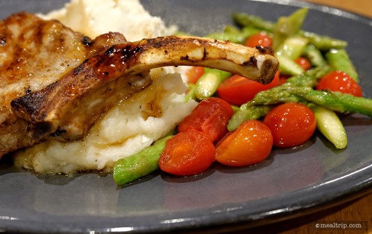 A closer look at the asparagus and tomato medley next to the bone-in pork chop.