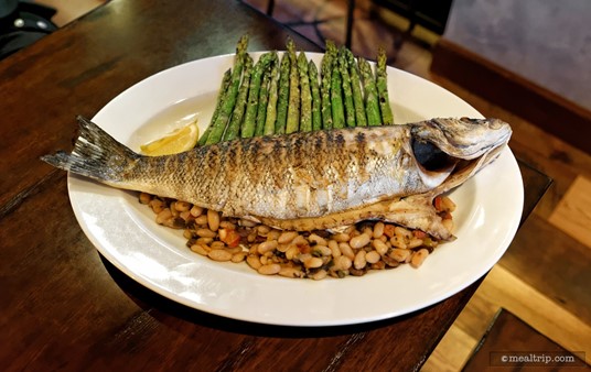 The "Grilled Whole Greek Sea Bass" Family-style Plate is served with Cannellini Bean Ragout, and Seasonal Vegetables (asparagus is pictured here).