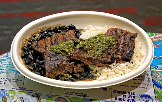 The Grilled Churrasco Steak is topped with chimichurri and served on a bed of black beans and rice.