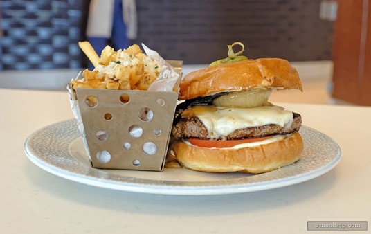 This is the Riviera Burger, and is one of about 10 food items available at Bar Riva. It's a beef patty burger and features a grilled portobello top, swiss cheese, caramelized onions and a tomato, all between a brioche roll. It's served with a side of fries that have been dusted with parmesan cheese and herbs.