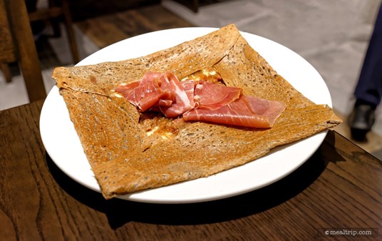 The Savoyarde Galette from La Crêperie de Paris includes Raclette Cheese, Caramelized Onions, Bacon, and imported Prosciutto Ham all wrapped in a buckwheat flour galette.