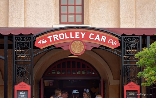 This is the Trolley Car logo sign over the front entrance of the building. There are two menu boards just outside the front entrance (near the bottom of the photo), but they don't really offer much specific information. It says things like "Hot and Cold Espresso Drinks" and "Fresh Brewed Coffee and Tea".