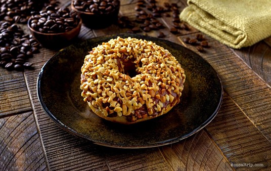 The Chocolate Peanut Crunch Doughnut is a "hole in the middle" style fried doughnut base with a chocolate ganache icing and is topped with crushed peanuts.