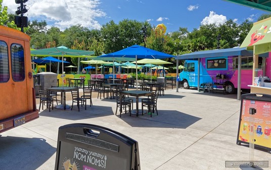 There are seven or eight umbrella covered tables located in the middle of the semi-circle that the food trucks form. 