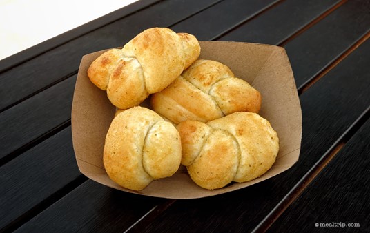 These are the Garlic Knots from the "Sides" portion of the Dockside Pizza menu. There's four Garlic Knots in the paper serving boat and they're topped with Garlic Butter.