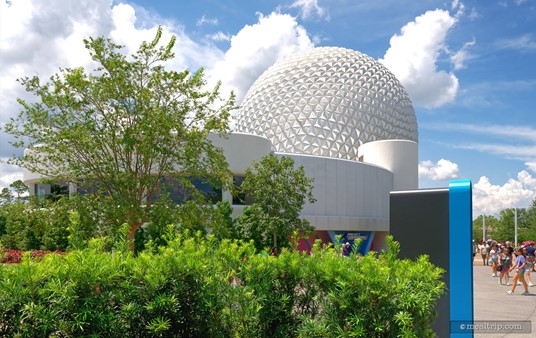 A few steps to the side and backwards finally brings most of the Spaceship Earth building into the photo – but now the Geo-82 building is behind a tree. Is it just me, or does it look like the clouds are trying to form a hidden Mickey with the Spaceship Earth building?